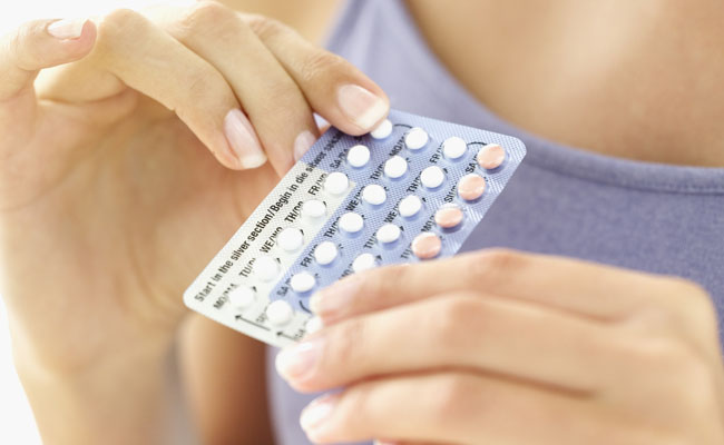 close-up of a young woman holding birth control pills