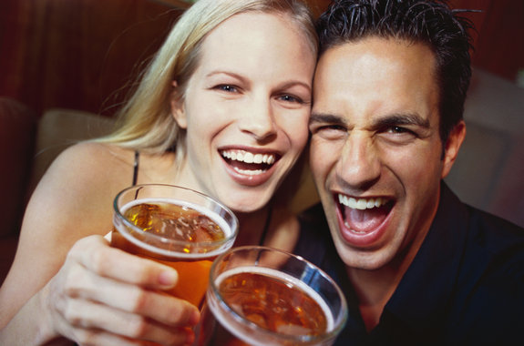 close-up of a young couple laughing with glasses of beer in their hands